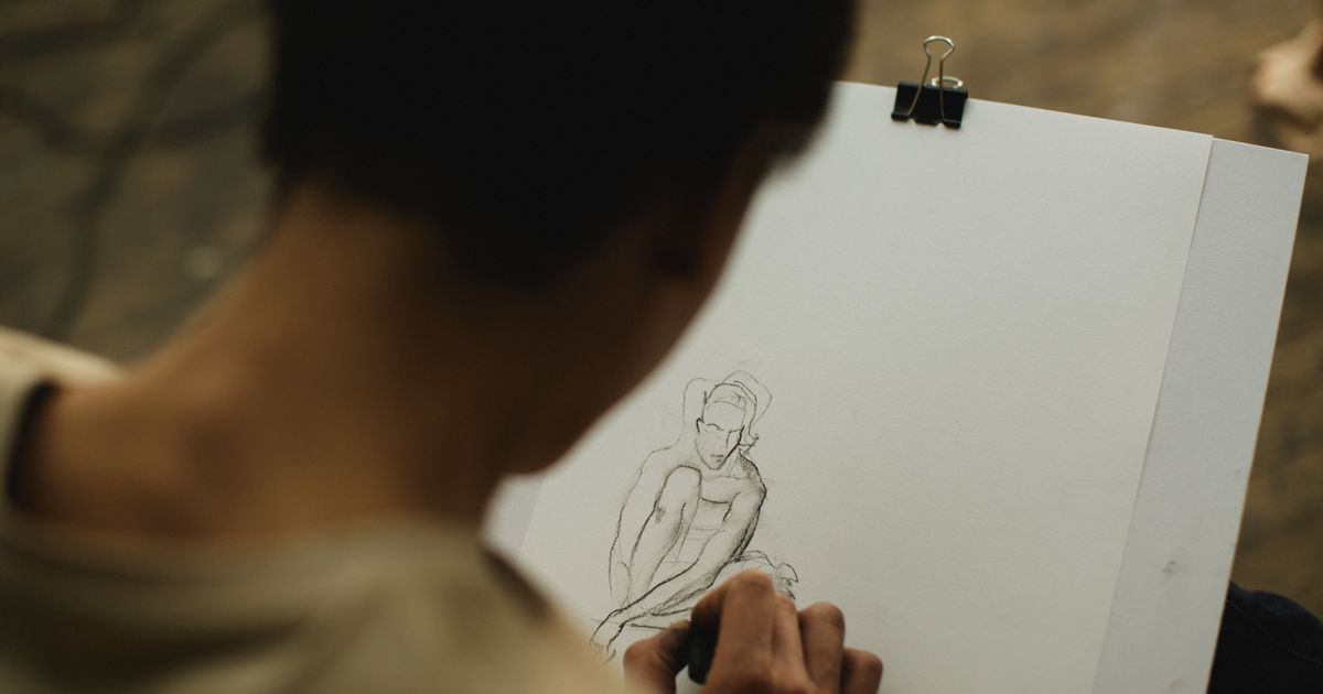 Artist making a loose charcoal sketch of a seated figure on paper clipped to a drawing board